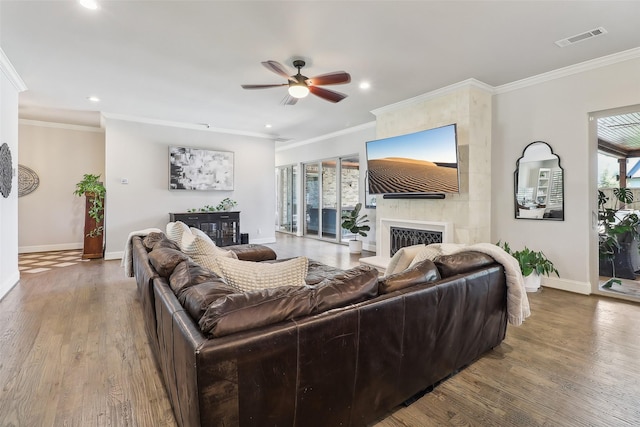 living room featuring ceiling fan, a large fireplace, baseboards, wood finished floors, and visible vents