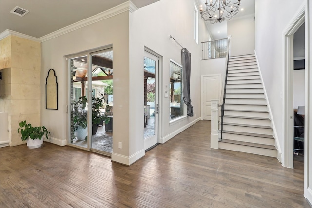 foyer featuring a chandelier, visible vents, ornamental molding, and wood finished floors