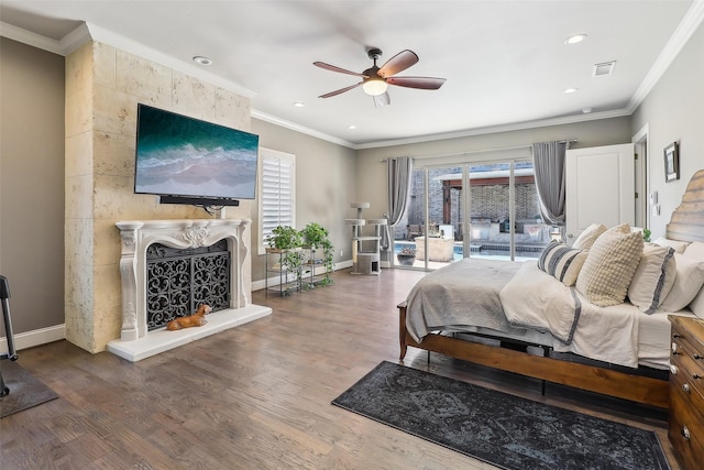 bedroom featuring visible vents, a fireplace, wood finished floors, and multiple windows