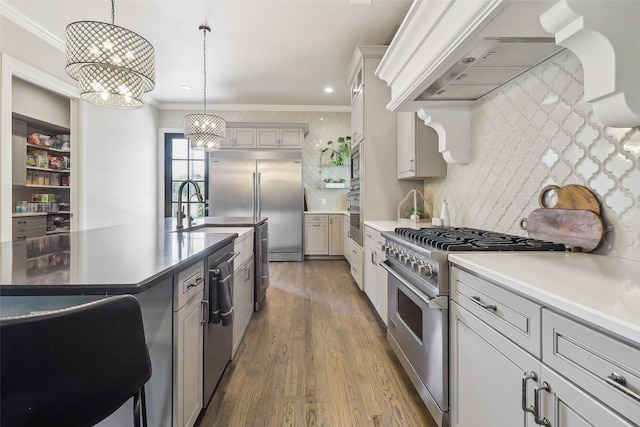 kitchen featuring a sink, built in appliances, premium range hood, and crown molding