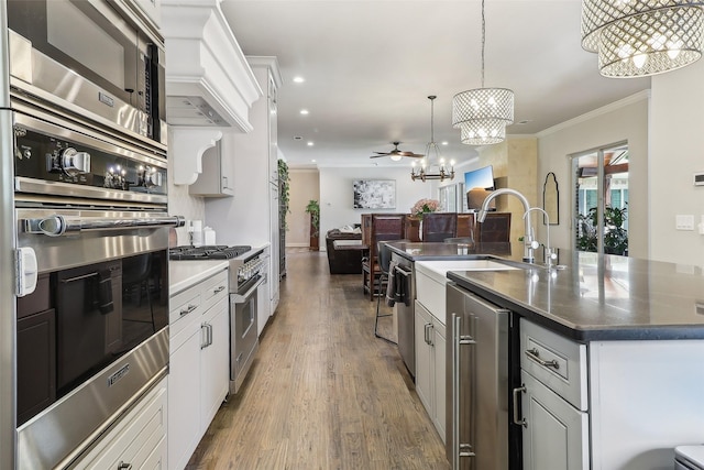 kitchen with ornamental molding, wood finished floors, recessed lighting, a notable chandelier, and stainless steel appliances