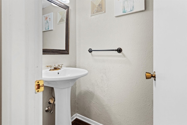 bathroom with visible vents, baseboards, and a textured wall
