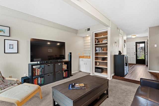 carpeted living room featuring visible vents, baseboards, and built in shelves