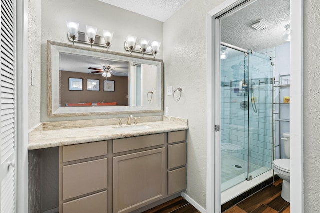 bathroom featuring a textured wall, toilet, a textured ceiling, a shower stall, and wood finished floors