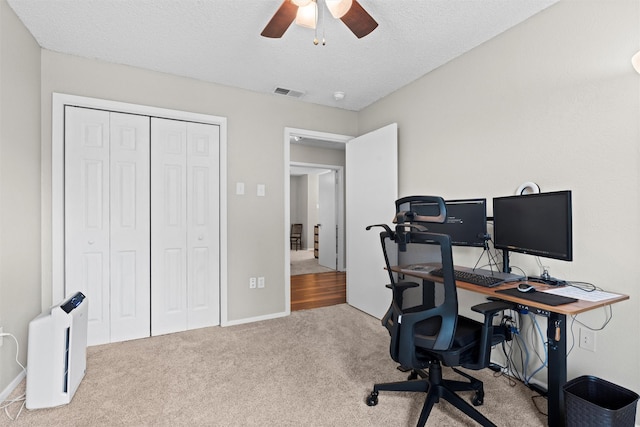 carpeted office featuring visible vents, a ceiling fan, a textured ceiling, and baseboards
