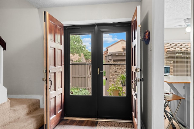 doorway with a textured ceiling, ceiling fan, french doors, and wood finished floors
