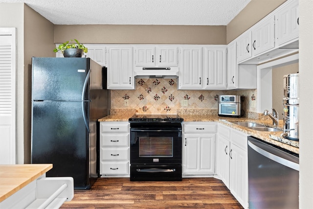 kitchen with under cabinet range hood, white cabinets, a sink, and black appliances