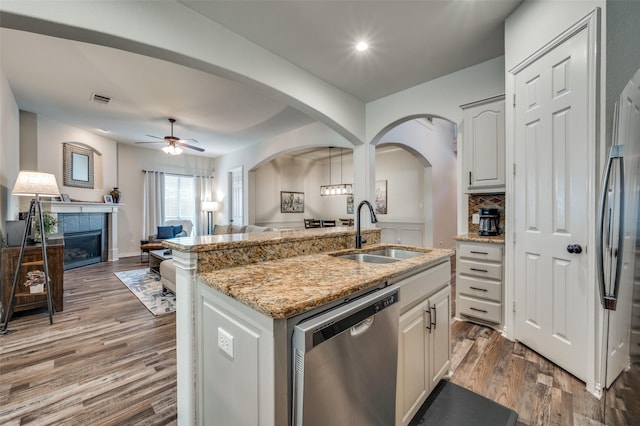 kitchen featuring ceiling fan, appliances with stainless steel finishes, a sink, a tiled fireplace, and open floor plan