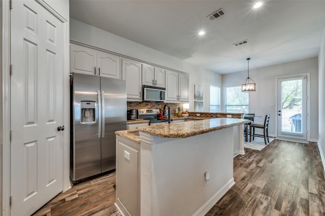 kitchen featuring dark wood-style flooring, stainless steel appliances, visible vents, and backsplash