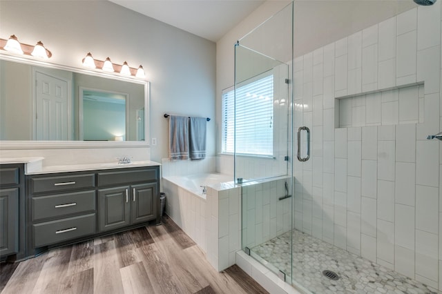 full bathroom with wood finished floors, a stall shower, a bath, and vanity