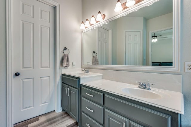full bathroom with double vanity, a ceiling fan, a sink, and wood finished floors