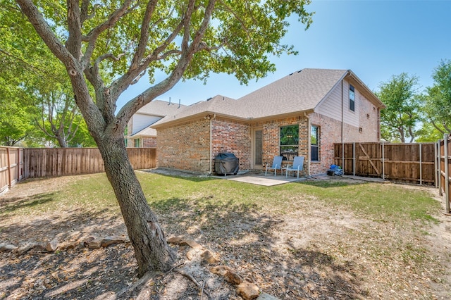 rear view of house featuring a lawn, brick siding, a fenced backyard, and a patio area
