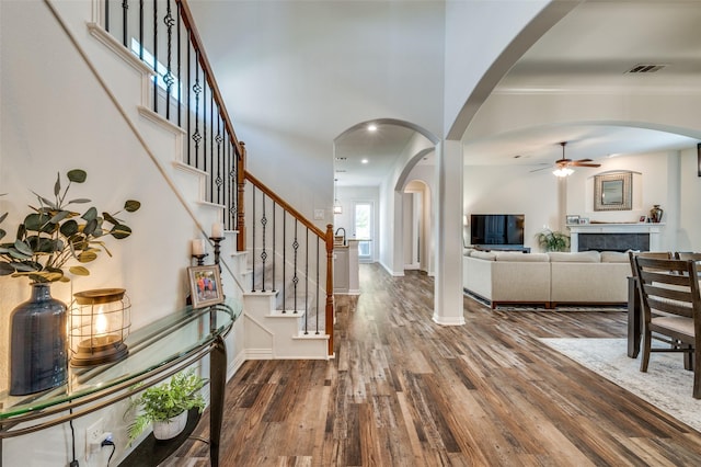 entrance foyer with visible vents, wood finished floors, baseboards, ceiling fan, and stairway