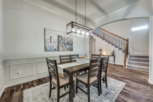 dining space featuring crown molding, dark wood finished floors, a wainscoted wall, baseboards, and stairs