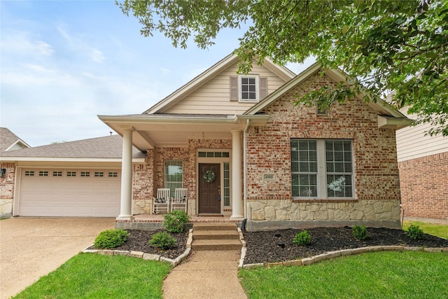 view of front of house featuring a porch, brick siding, an attached garage, and driveway