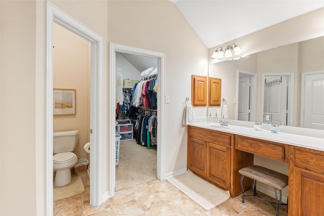 full bathroom featuring vanity, lofted ceiling, toilet, a walk in closet, and tile patterned floors