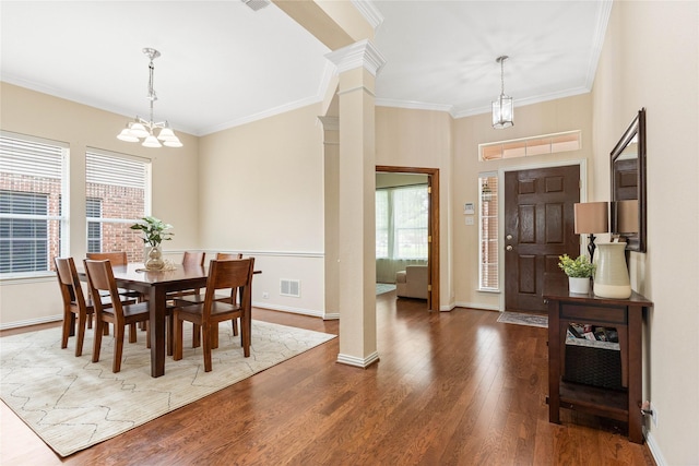 dining area featuring an inviting chandelier, crown molding, wood finished floors, and visible vents
