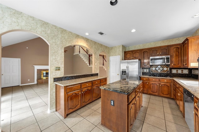 2806 Glenwick Ct, Richardson, TX 75082 - kitchen featuring appliances with stainless steel finishes, light tile patterned floors, dark stone counters, and a center island