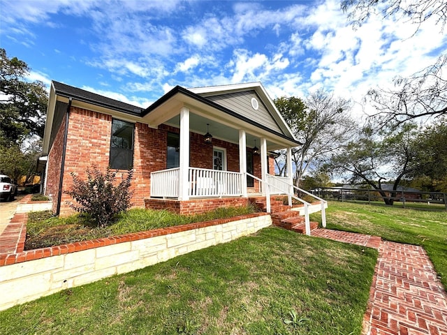 view of front of property featuring a porch, a front lawn, and brick siding