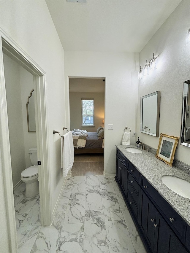 ensuite bathroom with connected bathroom, a sink, and marble finish floor