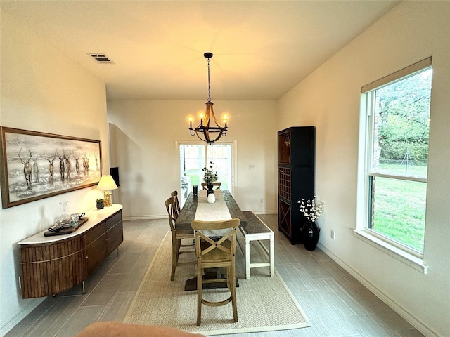 dining room featuring visible vents, baseboards, wood finished floors, and a notable chandelier