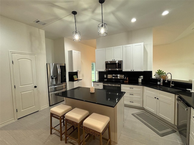 kitchen with a breakfast bar area, white cabinetry, appliances with stainless steel finishes, and a sink