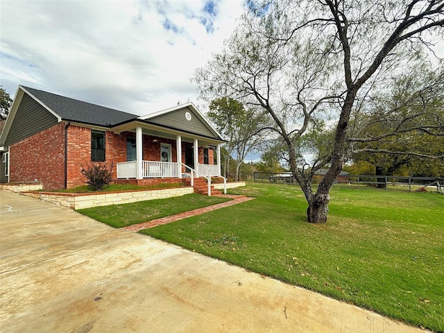 view of front of house with covered porch, brick siding, fence, a front lawn, and concrete driveway
