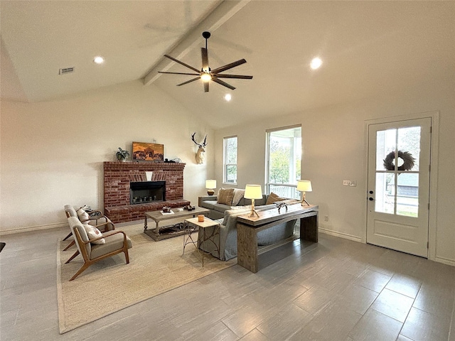 living room featuring visible vents, a brick fireplace, baseboards, vaulted ceiling with beams, and a ceiling fan