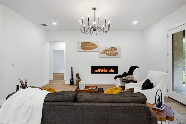 living room featuring a lit fireplace, visible vents, light wood-type flooring, a notable chandelier, and recessed lighting