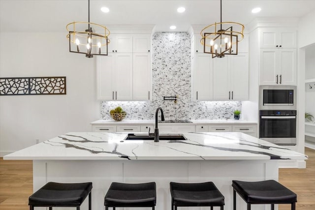 kitchen featuring a sink, appliances with stainless steel finishes, tasteful backsplash, and a notable chandelier
