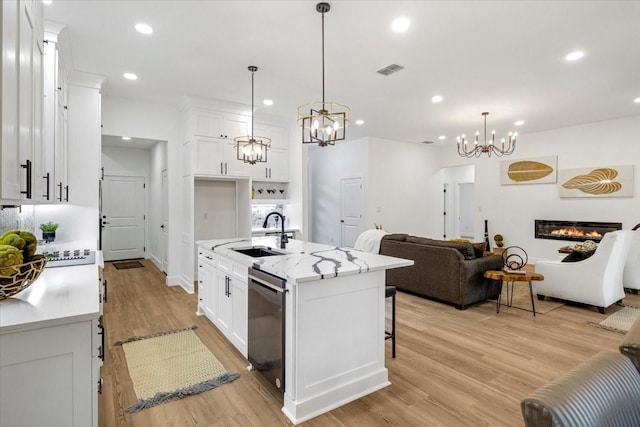 kitchen with a sink, dishwasher, a chandelier, open floor plan, and visible vents