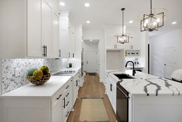 kitchen featuring a sink, black appliances, a chandelier, light wood-style floors, and an island with sink