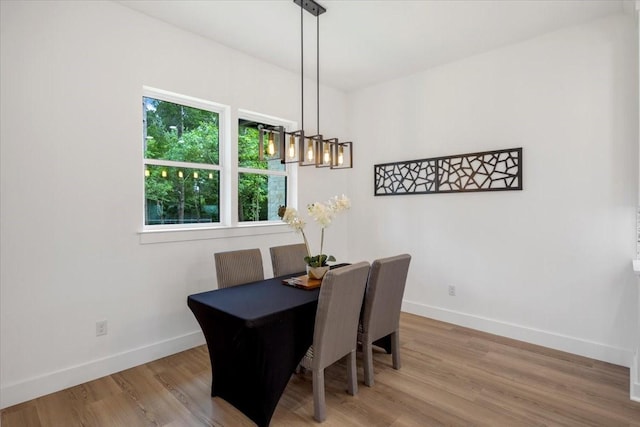 dining space with an inviting chandelier, baseboards, and wood finished floors