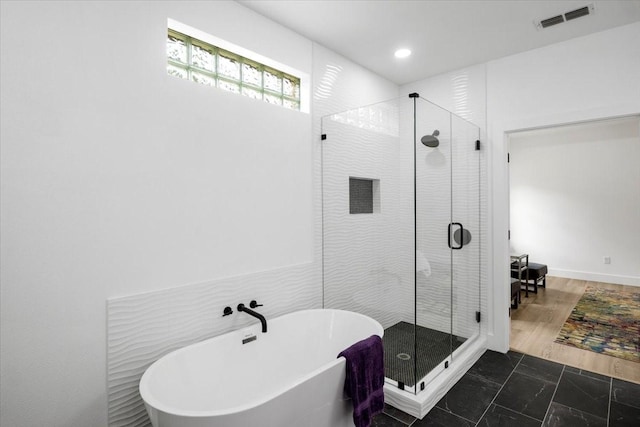 full bath with a freestanding tub, a stall shower, marble finish floor, and visible vents