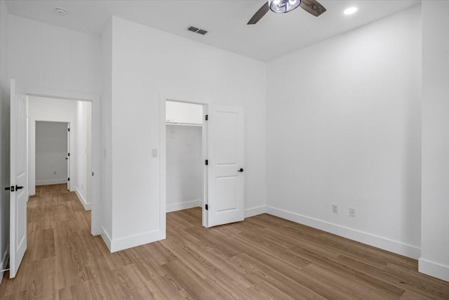 unfurnished bedroom with baseboards, a walk in closet, light wood-style flooring, and visible vents