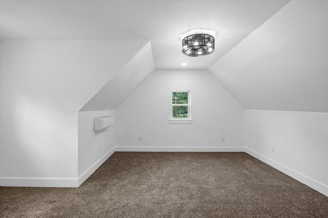 bonus room with baseboards, vaulted ceiling, and dark carpet