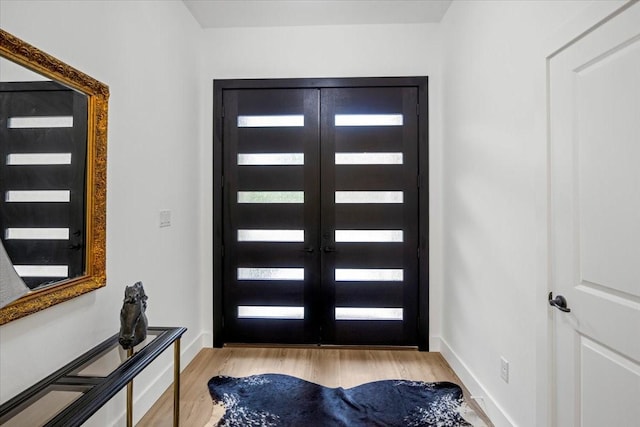 foyer entrance featuring baseboards, french doors, and wood finished floors