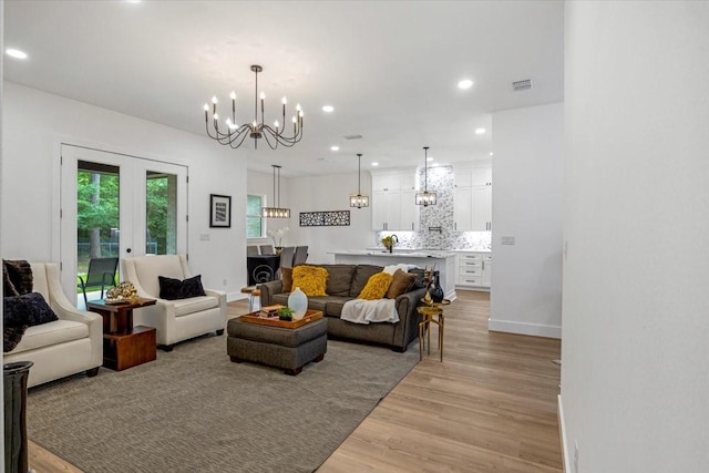 living room featuring light wood finished floors, a chandelier, french doors, recessed lighting, and visible vents