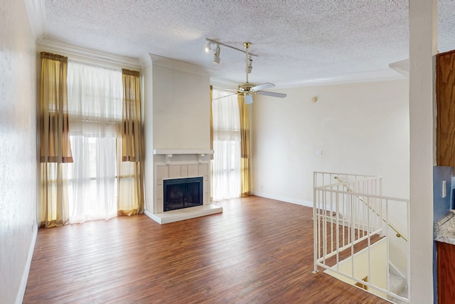 unfurnished living room featuring crown molding, a textured ceiling, wood finished floors, and a wealth of natural light