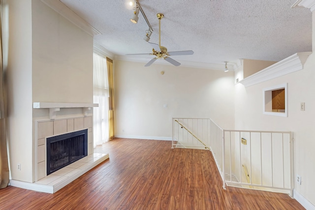 unfurnished living room featuring ceiling fan, rail lighting, a textured ceiling, and wood finished floors
