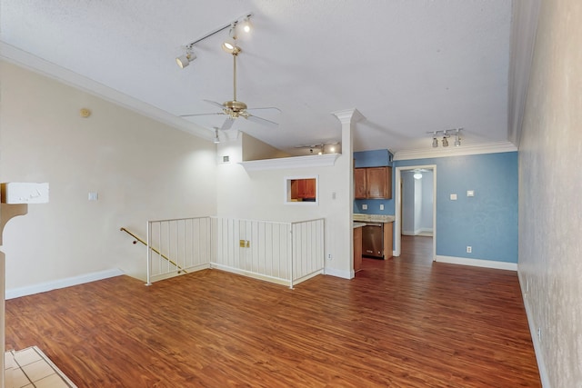 unfurnished living room with track lighting, a ceiling fan, dark wood-type flooring, and ornamental molding