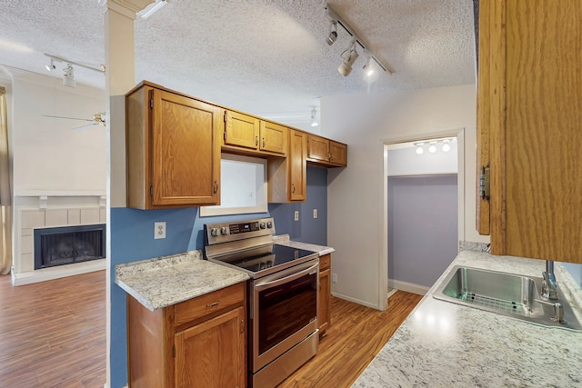 kitchen with a sink, a textured ceiling, rail lighting, a ceiling fan, and stainless steel electric stove