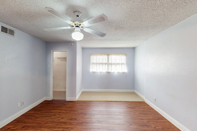unfurnished bedroom with ceiling fan, a textured ceiling, visible vents, wood finished floors, and a closet