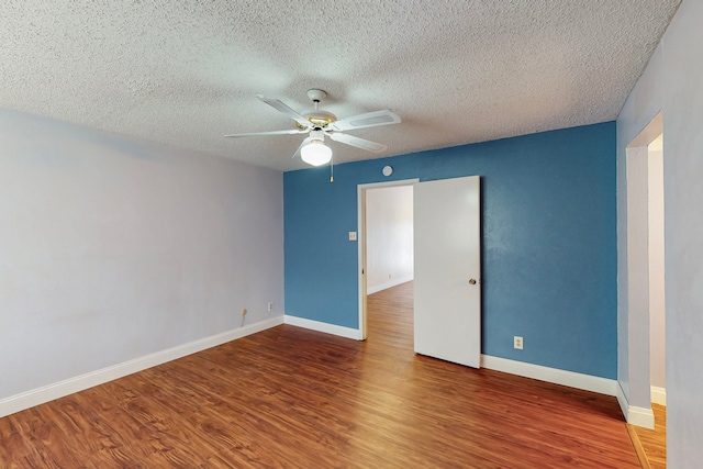 unfurnished room with baseboards, ceiling fan, a textured ceiling, and wood finished floors