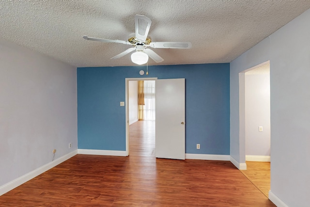 unfurnished room with baseboards, a ceiling fan, a textured ceiling, and wood finished floors