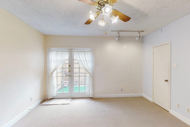 carpeted empty room with baseboards, ceiling fan, a textured ceiling, french doors, and rail lighting