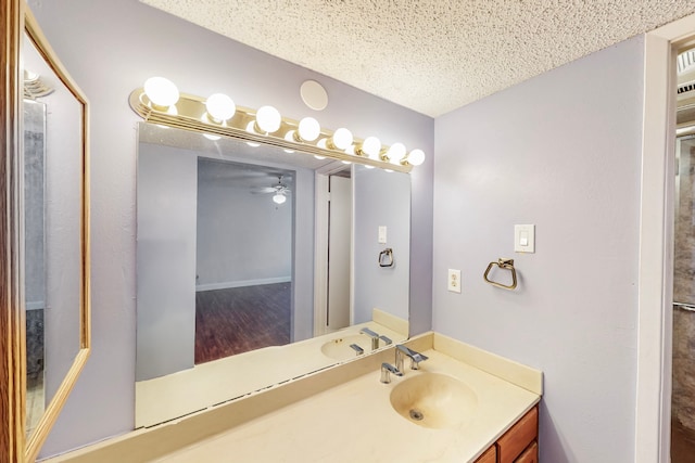 bathroom with a ceiling fan, a textured ceiling, and vanity