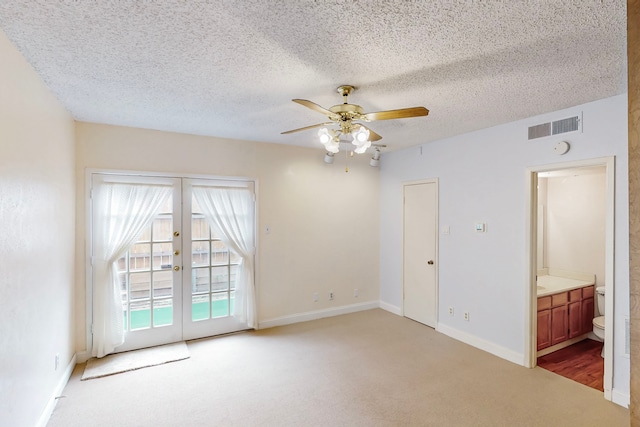 unfurnished room featuring visible vents, carpet floors, ceiling fan, a textured ceiling, and french doors