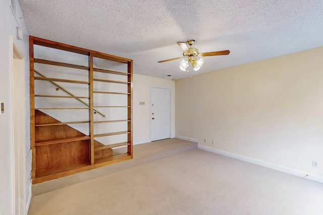 carpeted spare room featuring a ceiling fan, a textured ceiling, and baseboards
