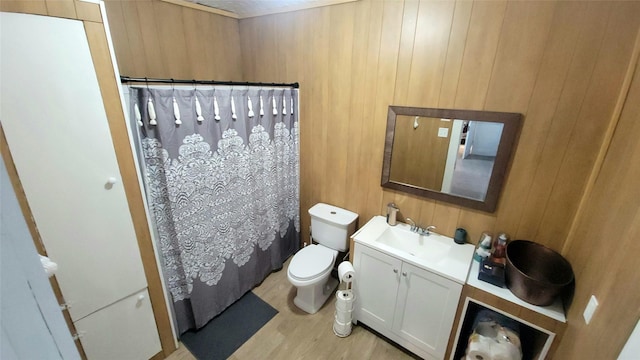 full bath with vanity, wood walls, wood finished floors, toilet, and a shower with curtain